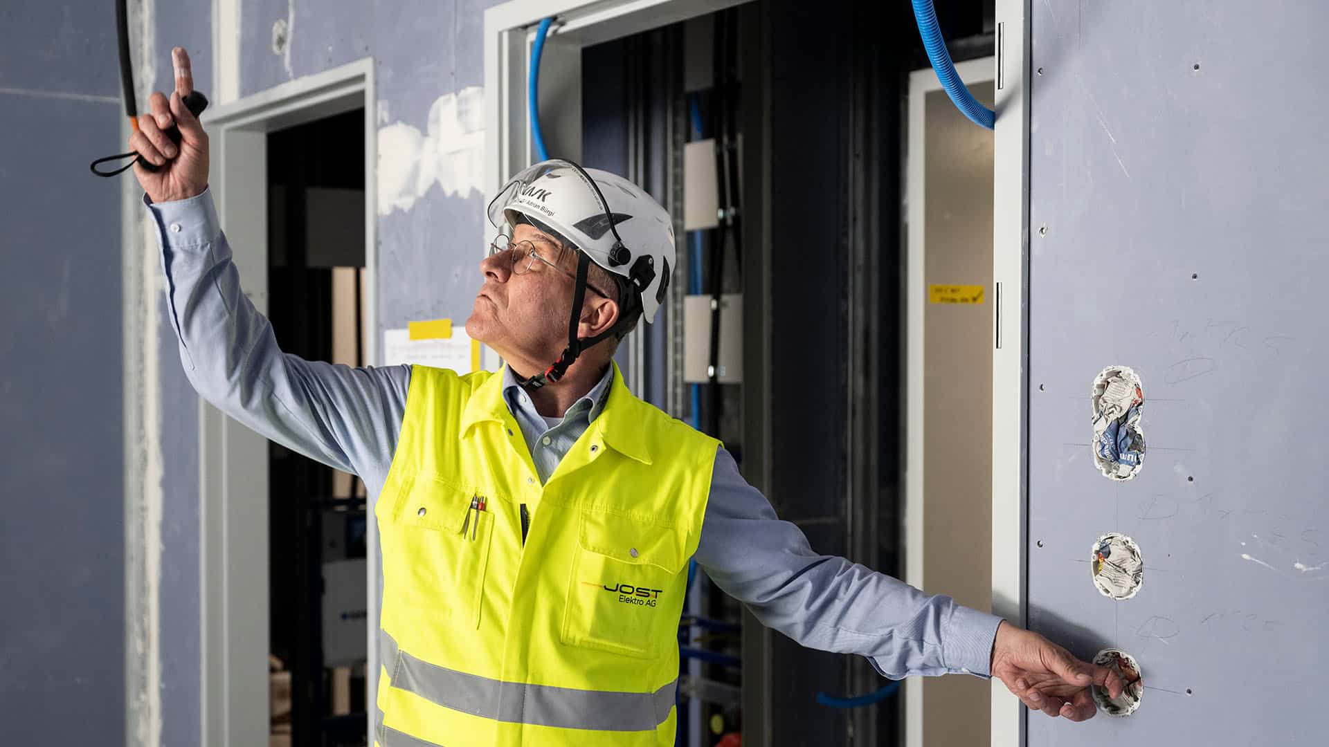 Adrian Bürgi, Jost Elektro AG, mit Bauhelm in Zimmer im KSB-Neubau
