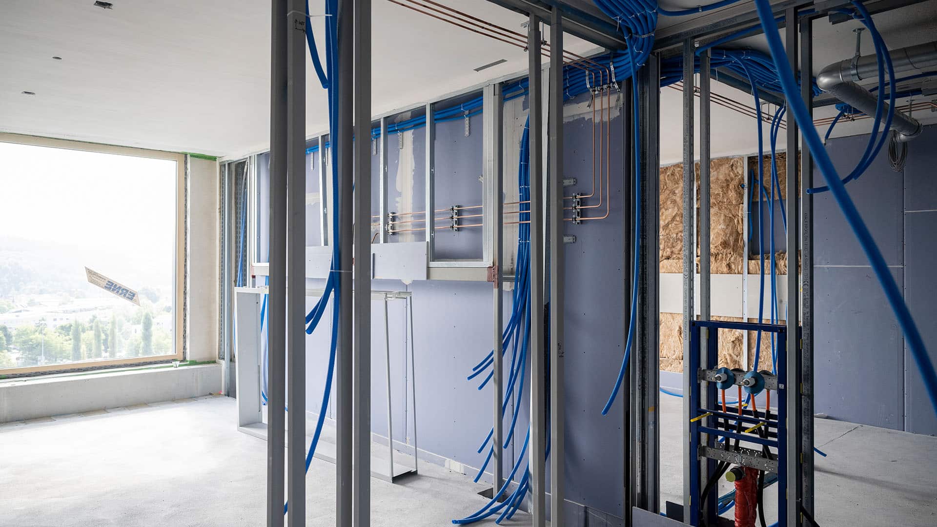Offene Wände mit blauen Rohren und Stützkonstruktionen im KSB-Neubau