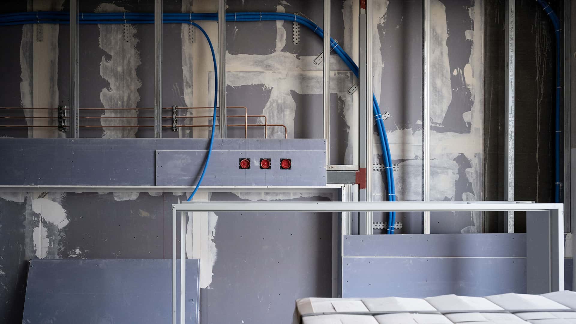 Einseitig beplankte Gipswand mit blauen Rohren im KSB-Neubau