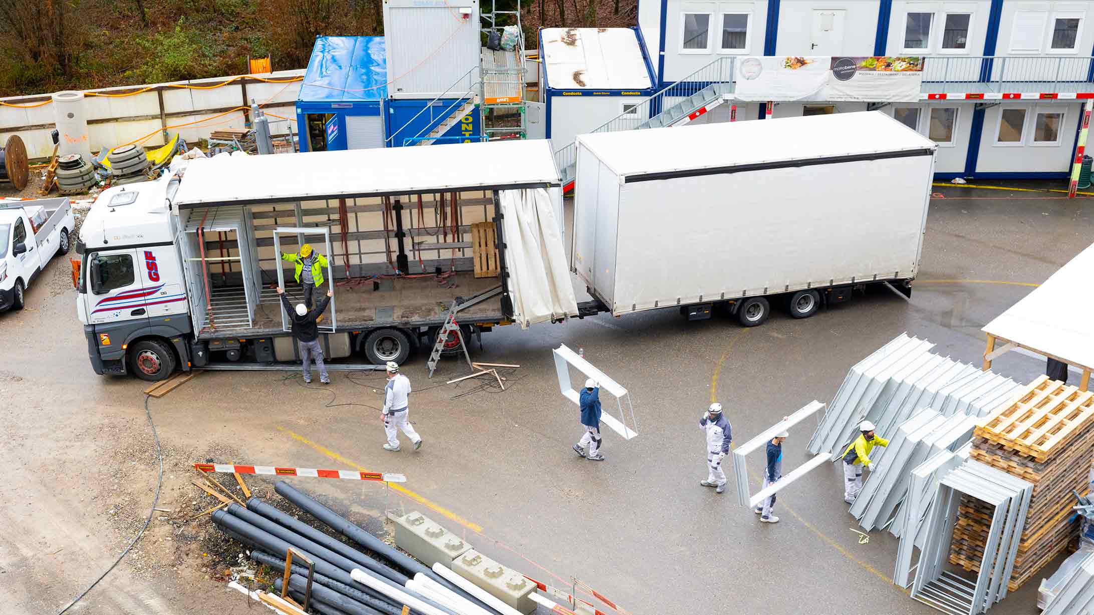 Bauarbeiter entladen Lastwagen, der Material auf KSB-Baustelle liefert
